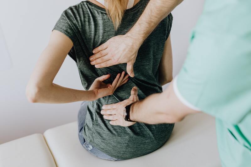 Woman having her back examined by practitioner for mid to lower back pain