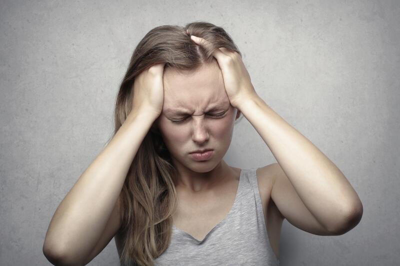 Woman holding her head in discomfort from headache or migraine